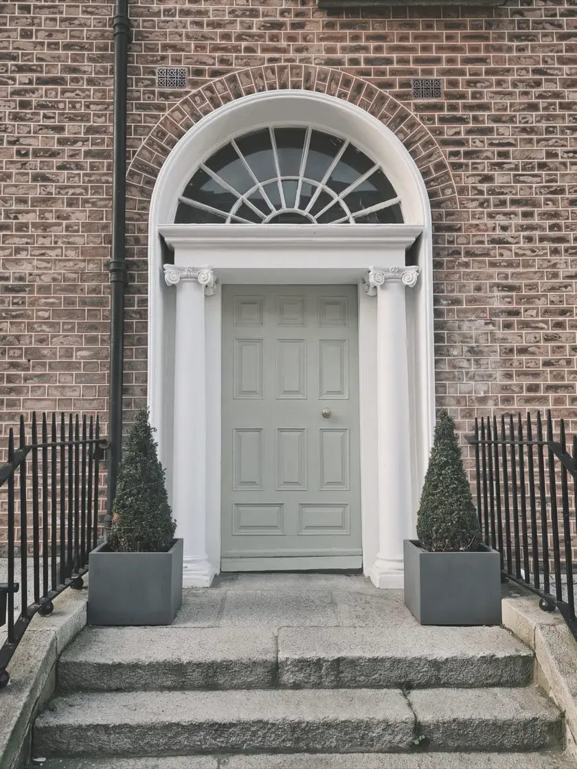 A Georgian doorway on a Dublin street: a panelled door beneath a fanlight, framed by granite steps and iron railings.